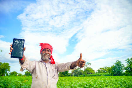 Indian farmer Showing a mobile screen at agriculture fieldの写真素材