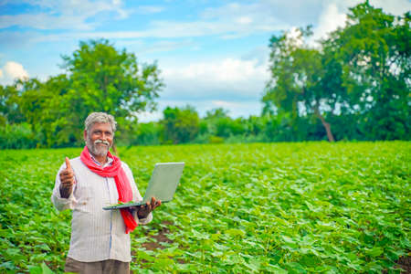 Indian farmer using a laptop at agriculture fieldの写真素材