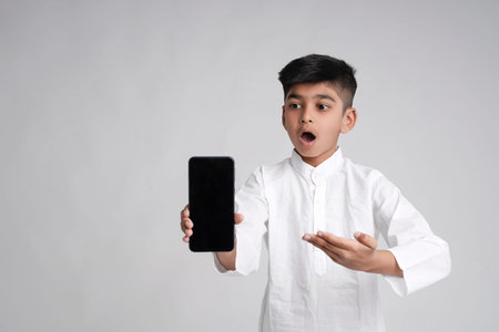 Cute indian little boy showing smart phone screen with copy space over white background