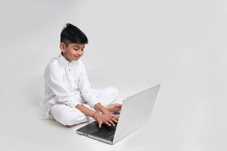 Cute indian boy using laptop over white backgroundの写真素材