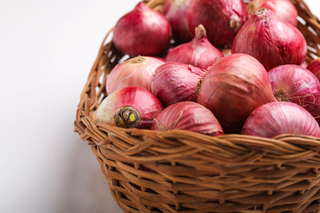 Red onions in wooden basket on white backgroundの写真素材