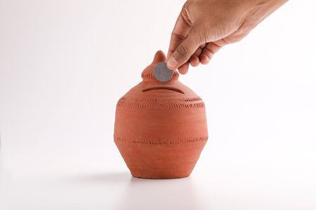 putting a coin into a clay money box: investments, retirement fund and banking conceptの写真素材