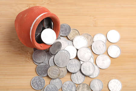 Clay piggy bank pot filled with Indian rupees coin over white background. saving conceptの写真素材