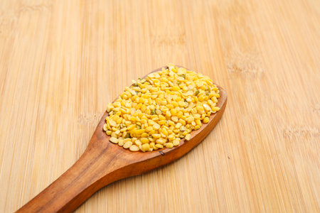 yellow moong mung dal lentil pulse bean in a wooden spoon.