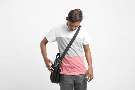 Indian college student holding laptop bag on white backgroundの写真素材