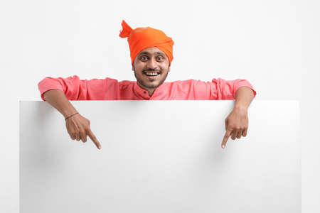 Young indian farmer holding white card board on white background.の写真素材