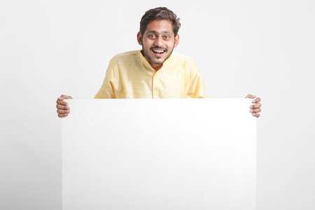 Indian man holding white board, promoting offers on festival season while wearing traditional cloths, standing over white background.の写真素材