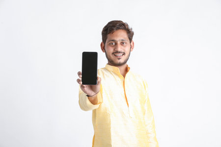 Young indian man in tradition wear and showing smartphone screen on white background.の写真素材