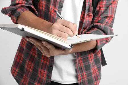 Education concept : Indian college student writing some notes in notebook on white background.