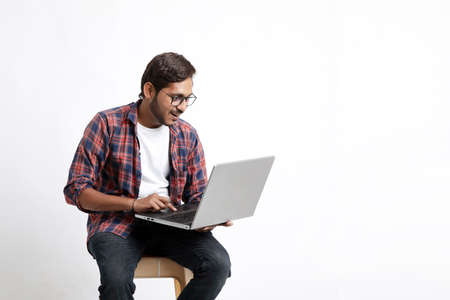 Indian college student using laptop on white background.の写真素材