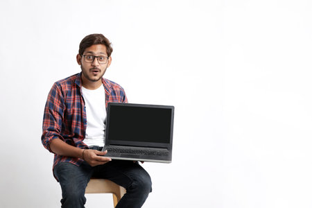Indian college student showing laptop screen on white background.の写真素材