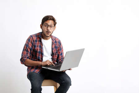 Young indian man using laptop and giving surprised expression.の写真素材