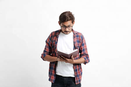 Indian college student reading book on white background.の写真素材