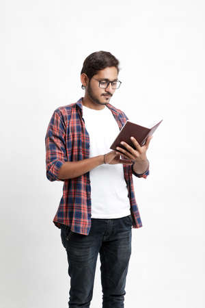 Indian college student reading book on white background.の写真素材