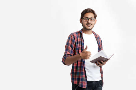 Education concept : Indian college student holding bag and showing note book on white background.の写真素材