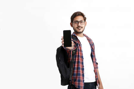 Young indian college student showing smartphone screen on white background.の写真素材
