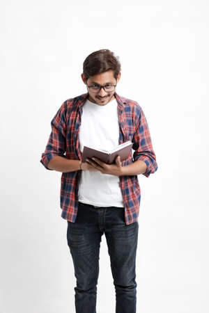 Indian college student reading book on white background.の写真素材