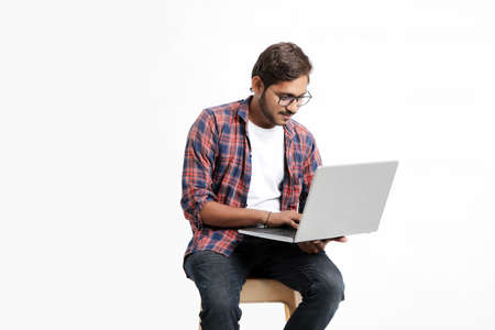 Indian college student using laptop on white background.の写真素材