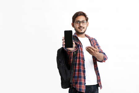 Young indian college student showing smartphone screen on white background.の写真素材