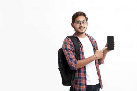 Young indian college student showing smartphone screen on white background.の写真素材
