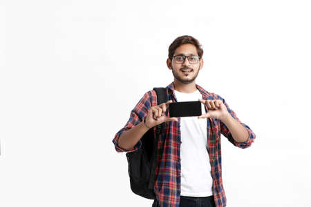 Young indian college student showing smartphone screen on white background.の写真素材