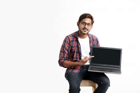 Indian college student showing laptop screen on white background.の写真素材