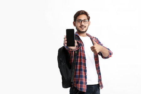 Young indian college student showing smartphone screen on white background.の写真素材