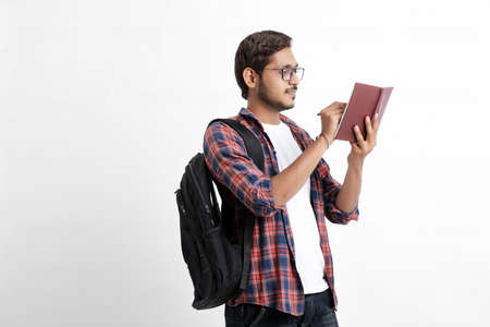 Education concept : Indian college student holding bag and showing note book on white background.の写真素材