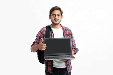 Indian college student showing laptop screen on white background.の写真素材