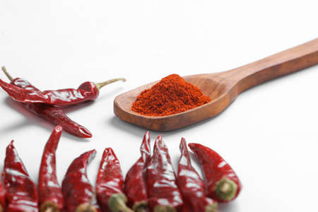 Chilli powder in wooden spoon with dry red chilly on white background.の写真素材