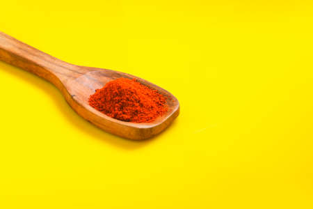 Chilli powder in wooden spoon with dry red chilly on yellow background.の写真素材