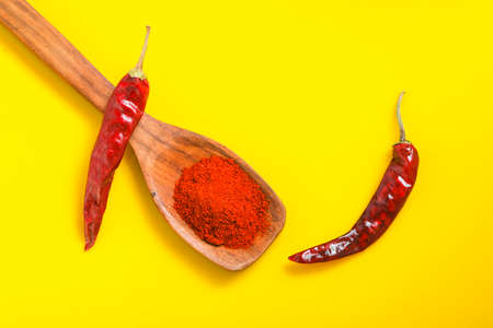 Chilli powder in wooden spoon with dry red chilly on yellow background.の写真素材