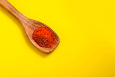 Chilli powder in wooden spoon with dry red chilly on yellow background.の写真素材