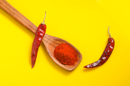 Chilli powder in wooden spoon with dry red chilly on yellow background.の写真素材