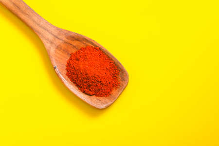 Chilli powder in wooden spoon with dry red chilly on yellow background.の写真素材