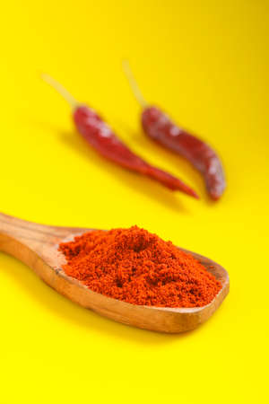 Chilli powder in wooden spoon with dry red chilly on yellow background.の写真素材