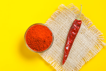Red chilli powder in glass bowl on yellow background. top viewの写真素材