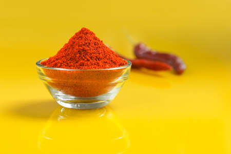 Red chilli powder in glass bowl on yellow background.の写真素材