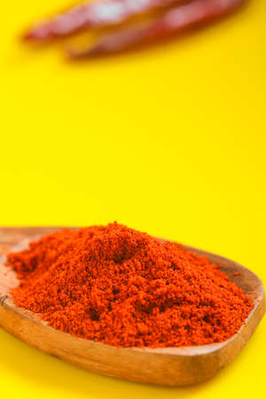 Chilli powder in wooden spoon with dry red chilly on yellow background.の写真素材