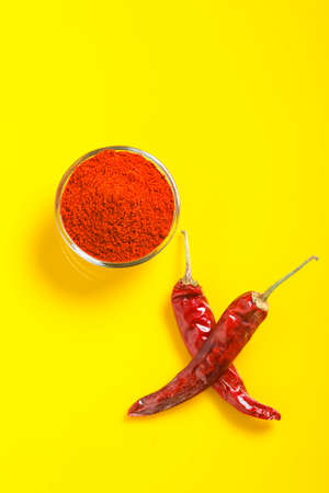 Dry Red chilli with chilli powder in glass bowl on yellow background.の写真素材