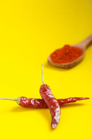 Chilli powder in wooden spoon with dry red chilly on yellow background.の写真素材