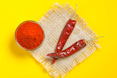 Red chilli powder in glass bowl on yellow background. top viewの素材 [FY310167481780]