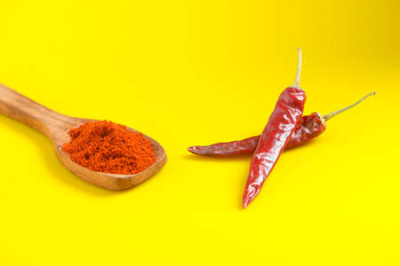 Chilli powder in wooden spoon with dry red chilly on yellow background.の写真素材