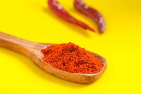 Chilli powder in wooden spoon with dry red chilly on yellow background.の写真素材