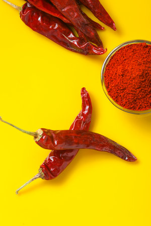 Dry Red chilli with chilli powder in glass bowl on yellow background.の写真素材