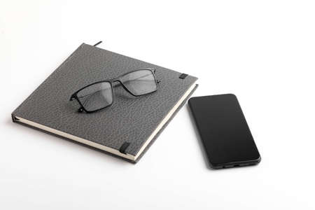 Smartphone, diary and spectacles on whiteの写真素材