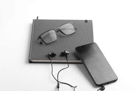 Work from home concept. Smartphone, diary and earphone on whiteの写真素材