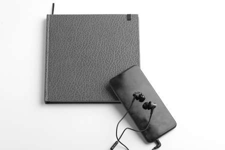 Work from home concept. smartphone, diary and earphone on whiteの写真素材