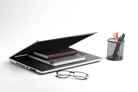 Modern workspace with laptop keyboard, notebook, spectacles on whiteの写真素材