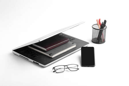 Modern workspace with laptop keyboard, notebook, spectacles on whiteの写真素材